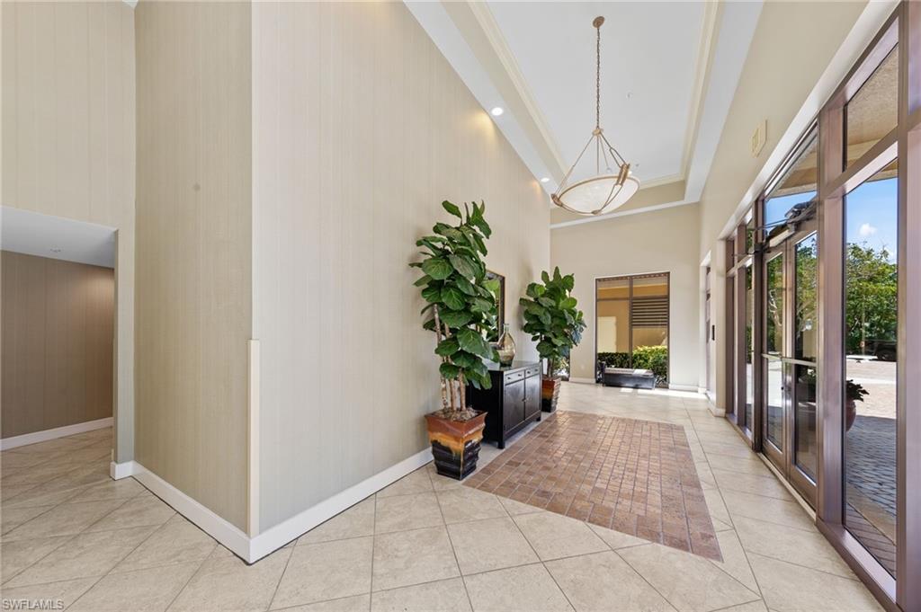 The entry features large format tile flooring, a tray ceiling with a hanging light fixture, and floor-to-ceiling windows