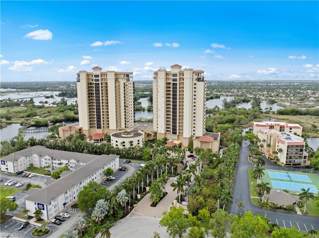 Aerial view showcasing two prominent high-rise buildings and several low-rise properties, surrounded by lush greenery and bodies of water