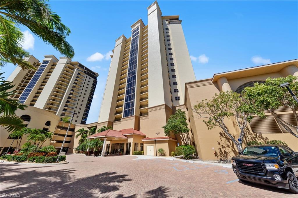 The property features a tall, cream-colored building with numerous windows and balconies, complemented by a red-tiled entrance canopy