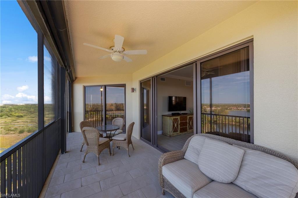 The screened balcony features a ceiling fan, tiled flooring, and views of a body of water and the surrounding landscape