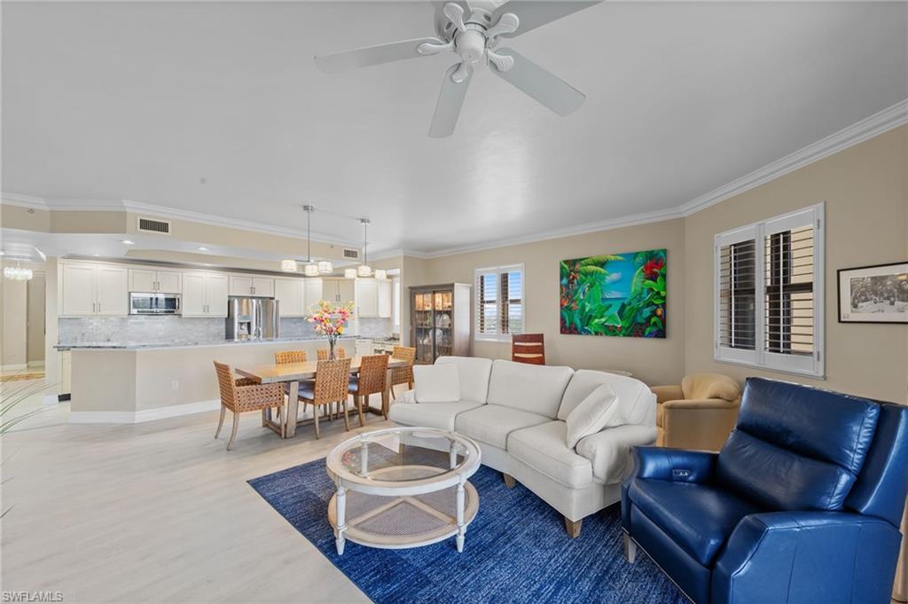 The open-concept living area features light-colored flooring, a ceiling fan, and crown molding