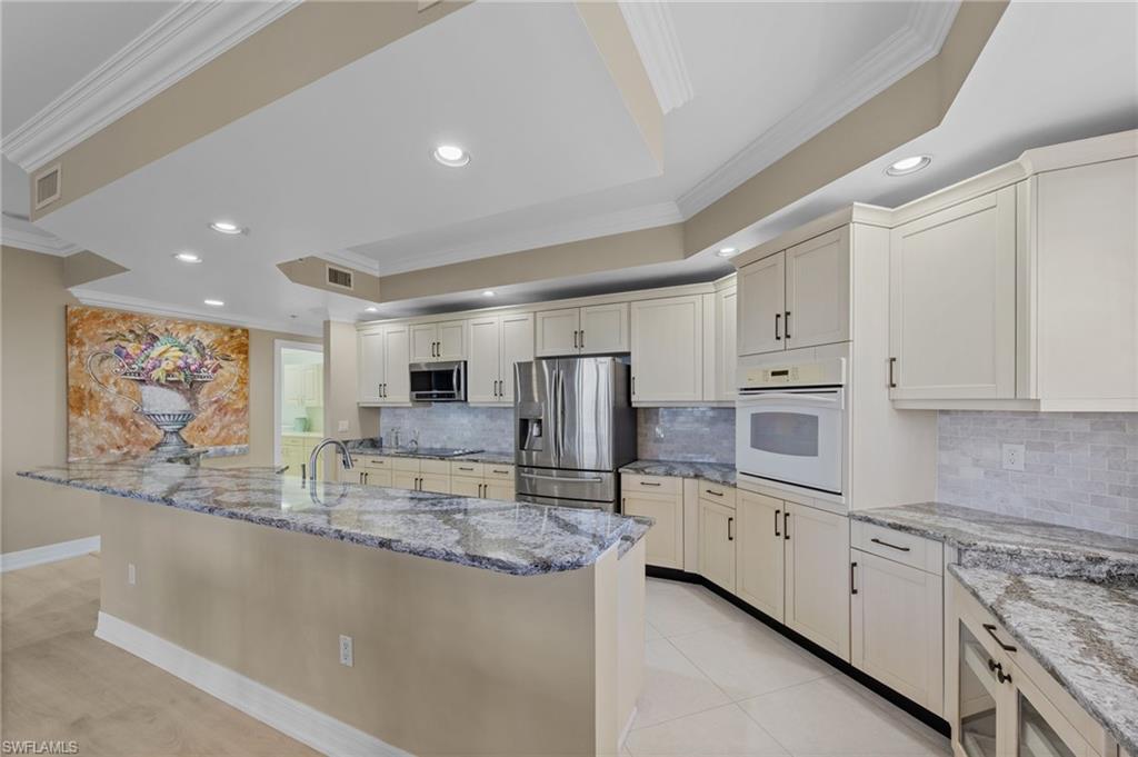 The kitchen features an expansive island with granite countertops, light-colored cabinetry, stainless steel appliances, and recessed lighting