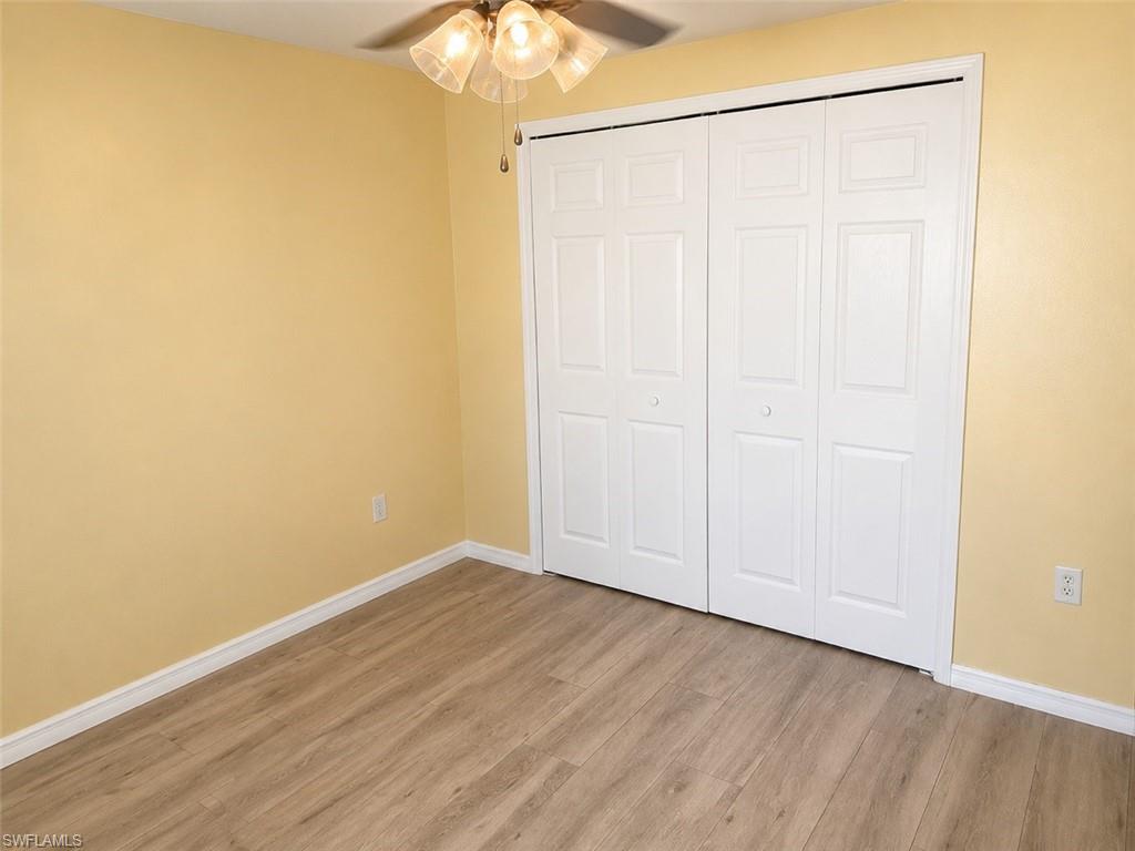 Room featuring wood-finish flooring, light yellow walls, white baseboards, and a ceiling fan with integrated lighting