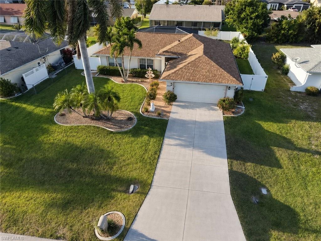 Single-story residence featuring a shingled roof, two-car garage, concrete driveway, and white perimeter fencing