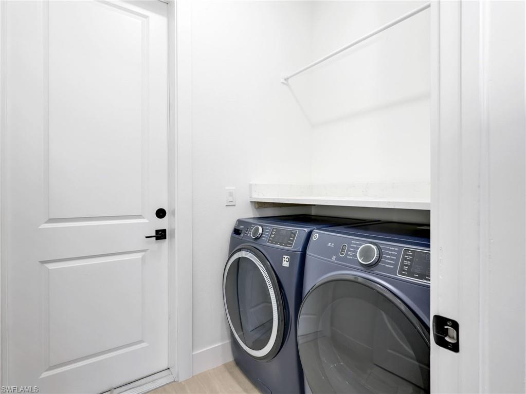 Dedicated laundry area featuring a built-in shelf, hanging rod, and light-toned flooring