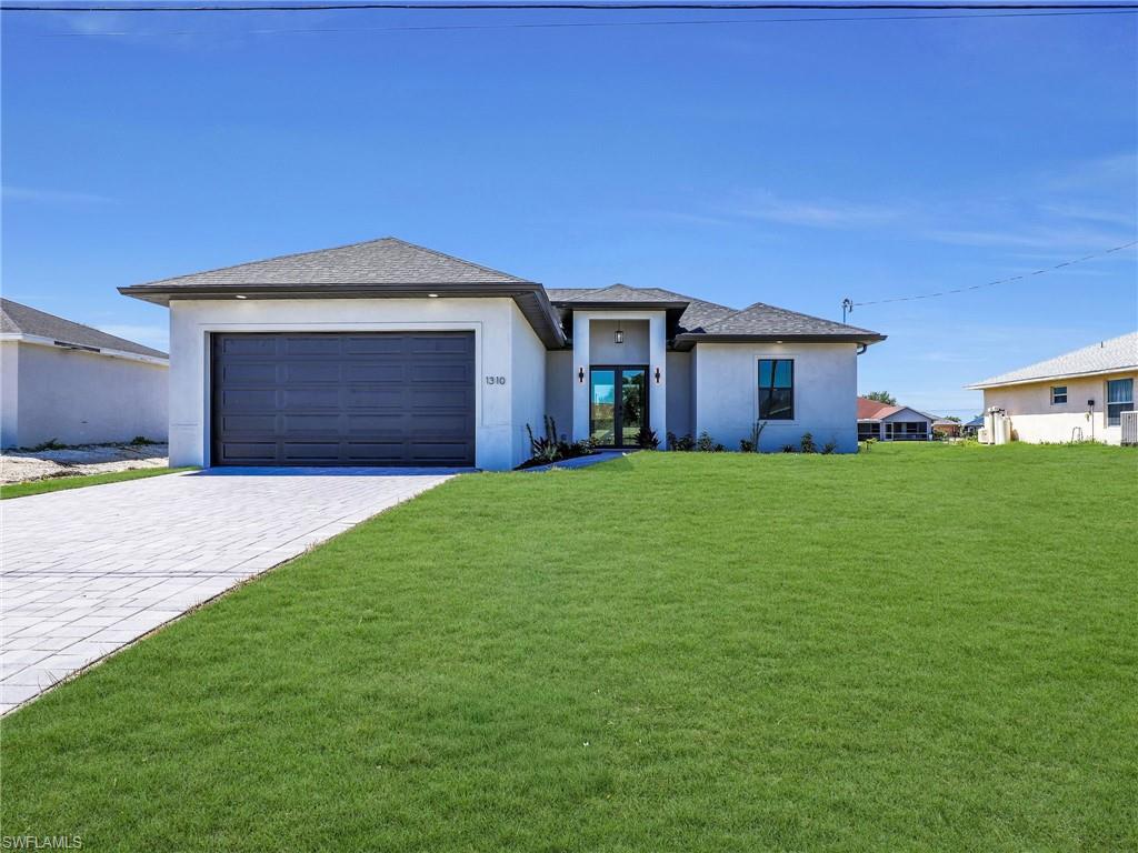 Contemporary stucco exterior with a dark garage door and a contrasting paver driveway  the color of the grass has been virtually enhanced