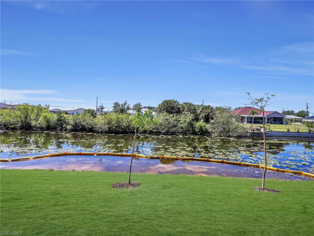 Manicured lawn bordering a waterway with established trees, reflecting a clear blue sky  The color of the grass has been virtually enhanced