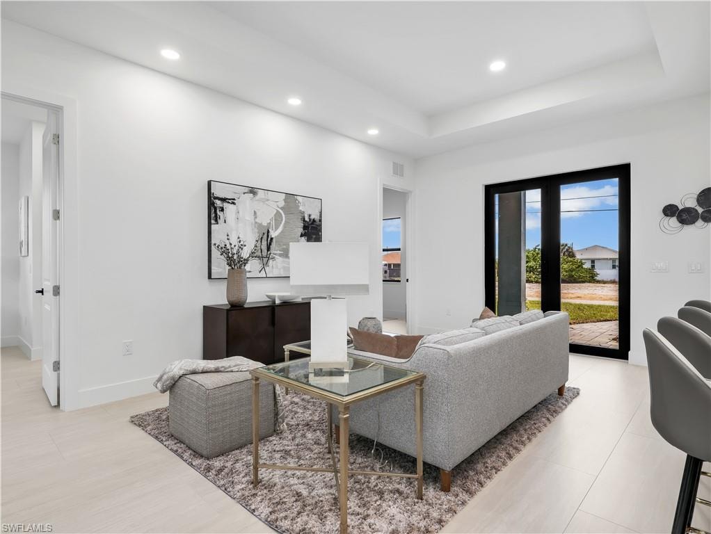 Spacious living area featuring light-toned flooring, recessed lighting, and a tray ceiling  photos used from another listing to show what it would look like with furniture