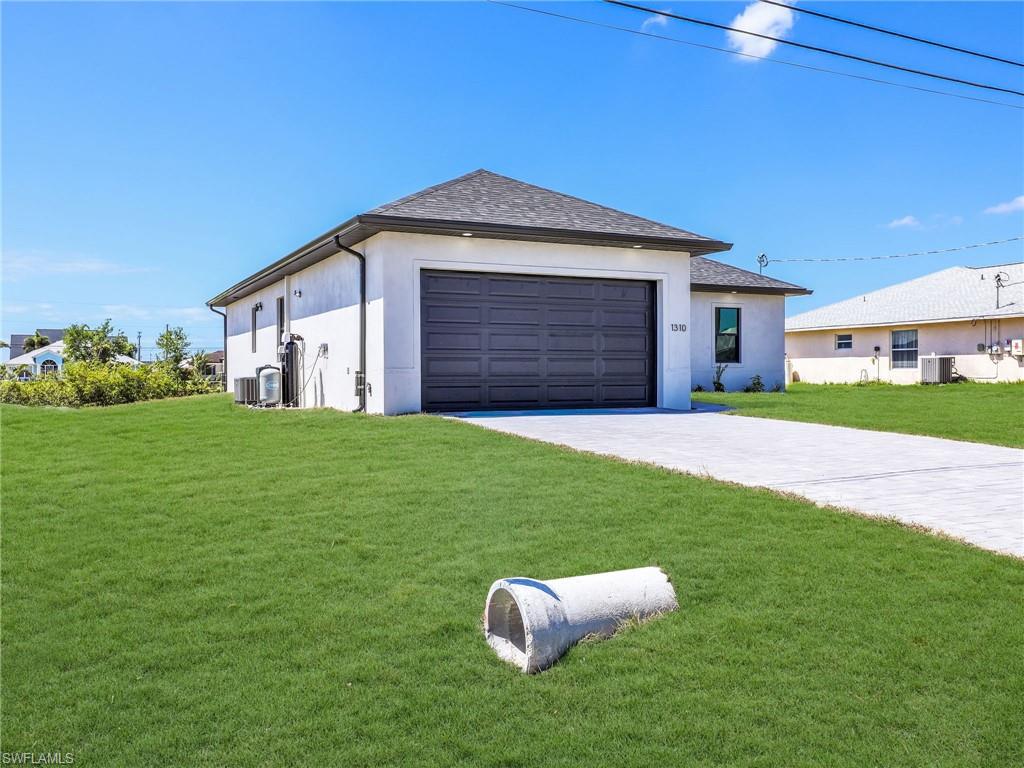 Contemporary stucco exterior with a dark garage door and a contrasting paver driveway  the color of the grass has been virtually enhanced