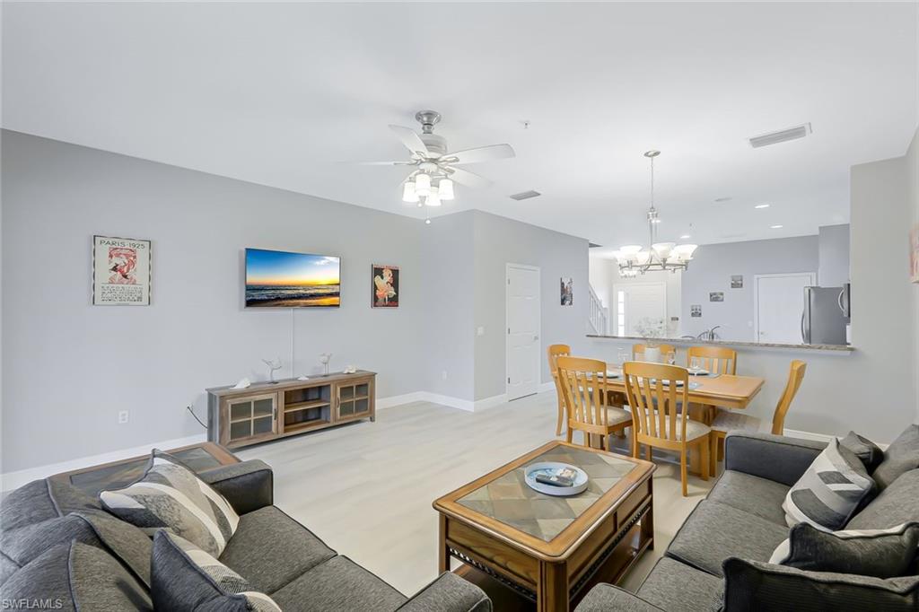 Living room with ceiling fan with notable chandelier, light hardwood / wood-style floors, and sink