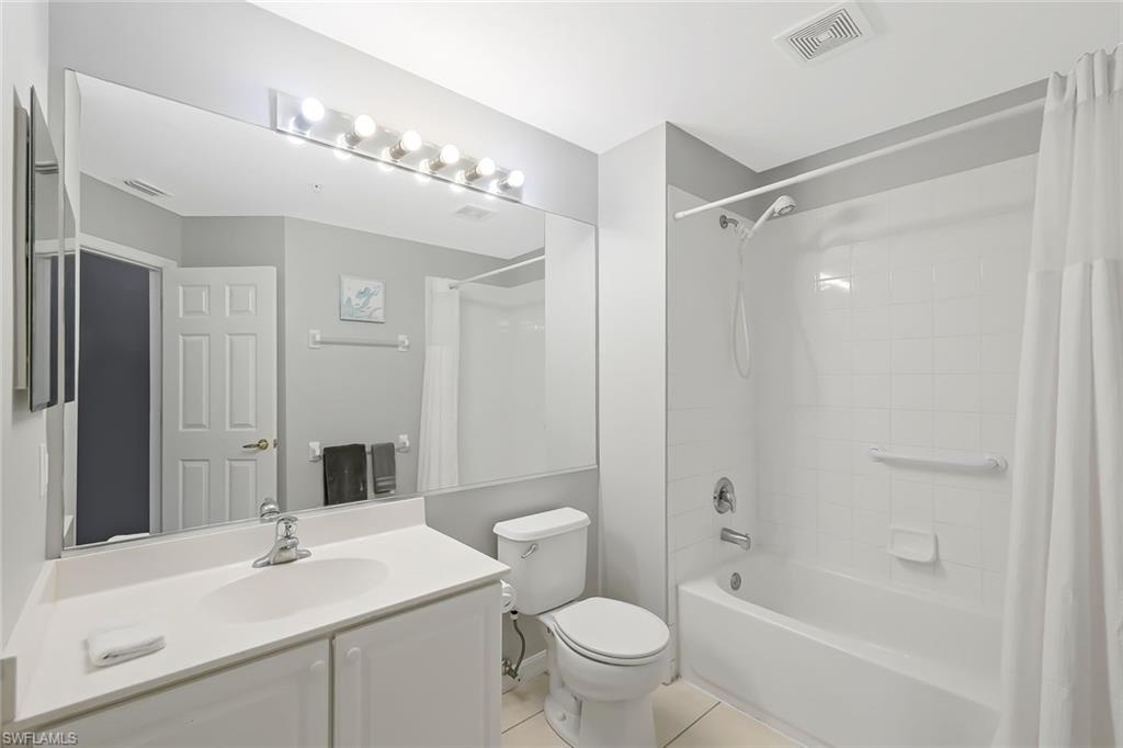 Full bathroom with tile floors, shower / bath combination with curtain, vanity, and toilet