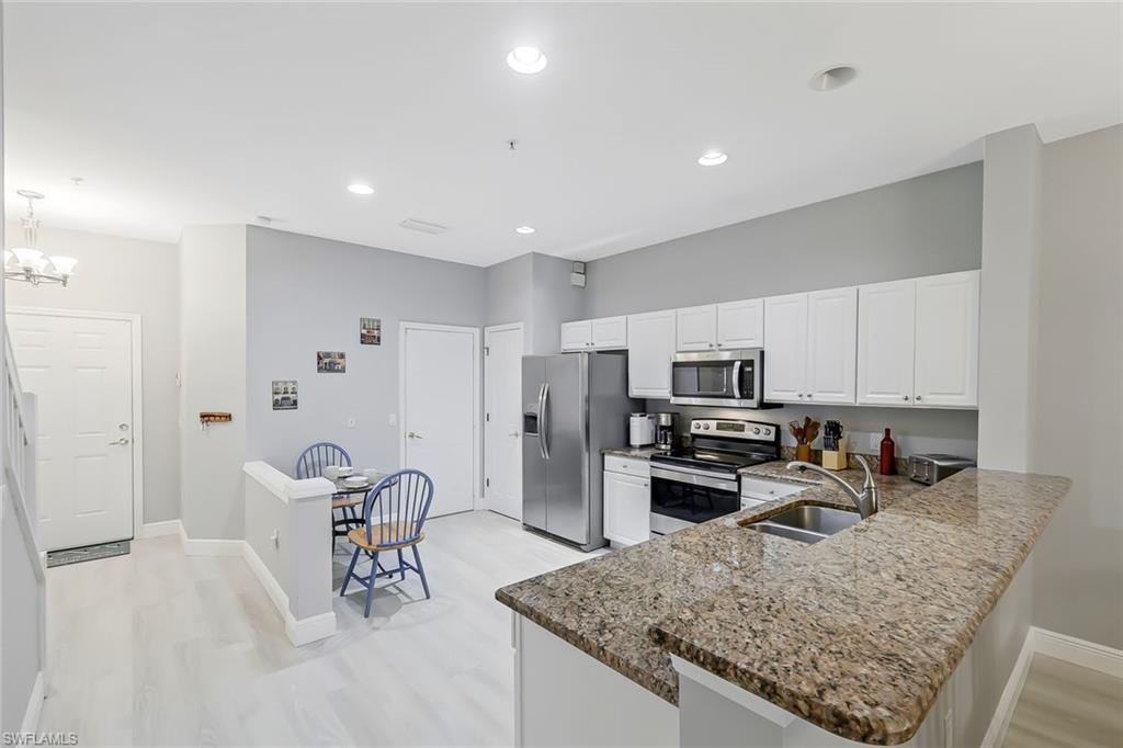 Kitchen with light wood-type flooring, appliances with stainless steel finishes, kitchen peninsula, pendant lighting, and sink