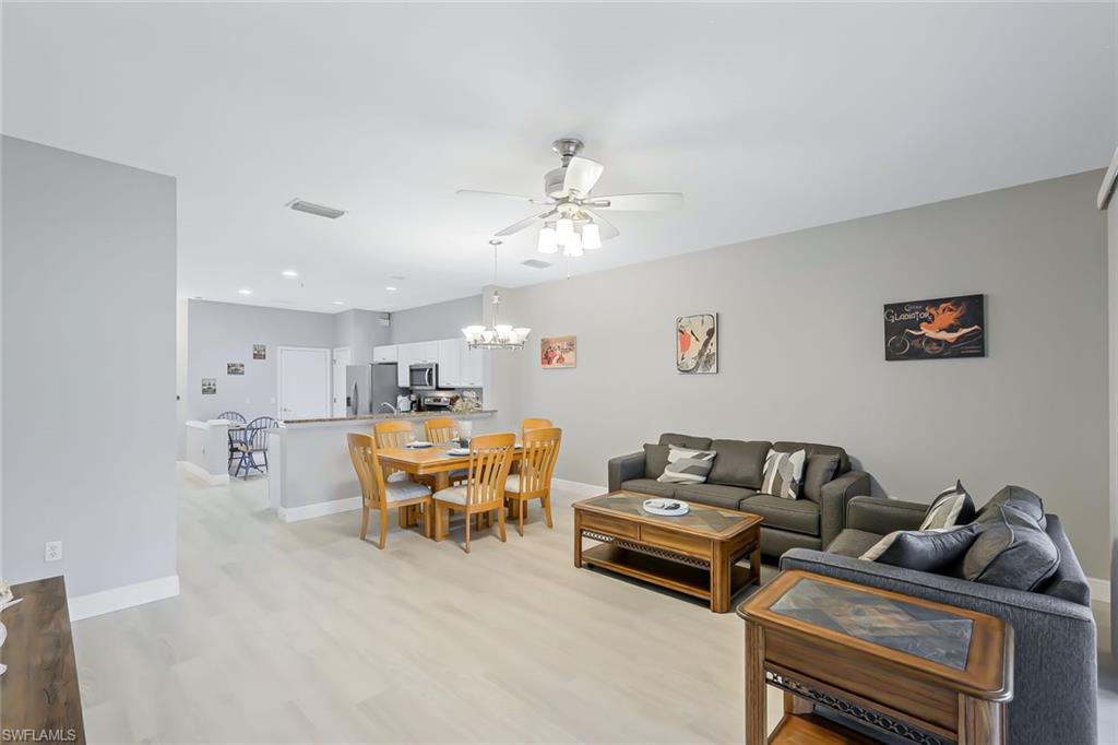 Living room featuring light wood-type flooring and ceiling fan with notable chandelier