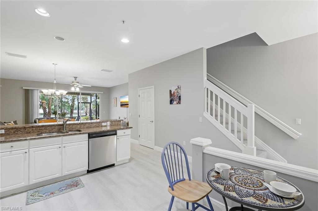 Kitchen with dark stone counters, stainless steel dishwasher, light wood-type flooring, sink, and white cabinetry