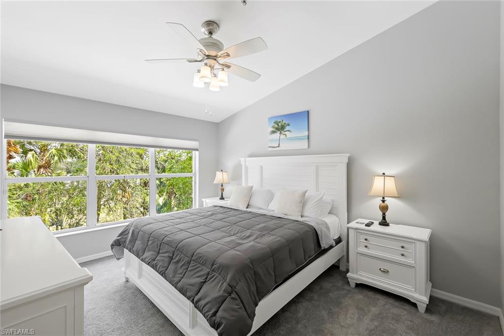 Bedroom featuring ceiling fan, dark colored carpet, and lofted ceiling