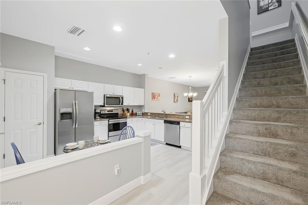 Kitchen featuring white cabinetry, light hardwood / wood-style floors, pendant lighting, and stainless steel appliances