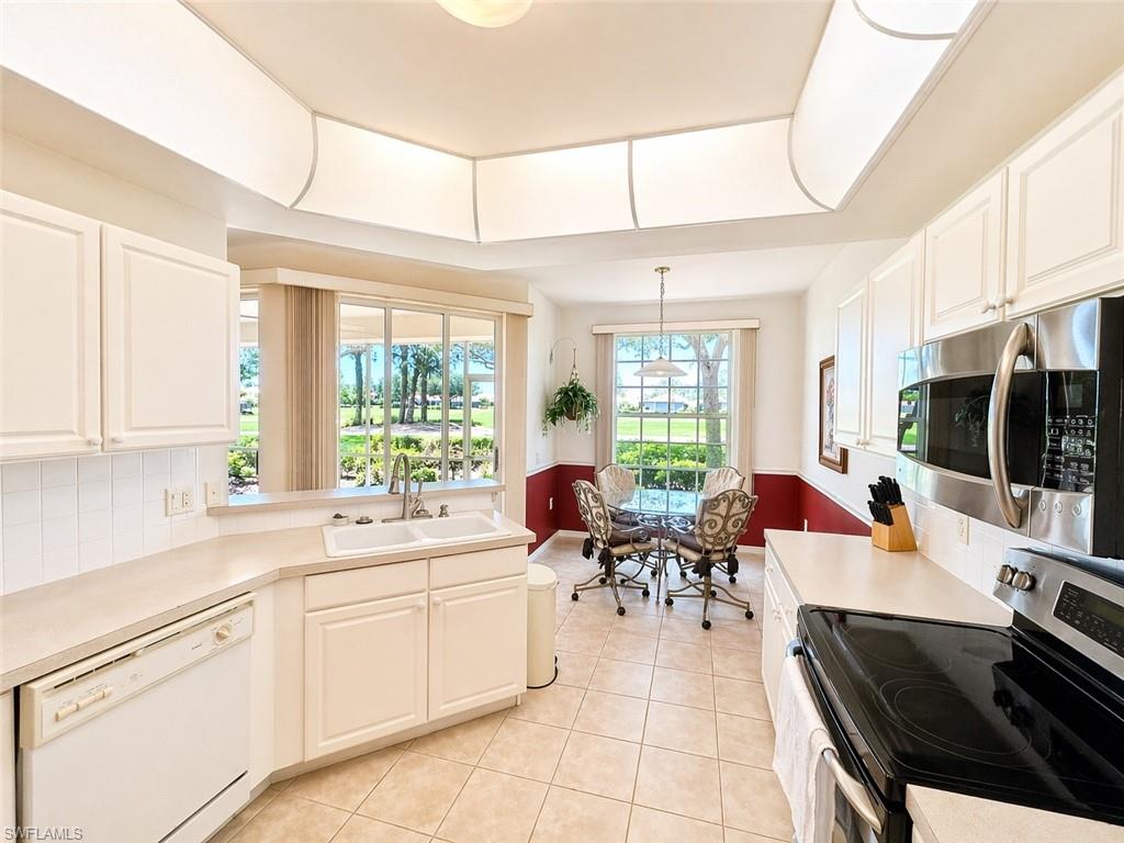 Well-maintained kitchen with ample cabinetry, solid surface counters, and breakfast bar.