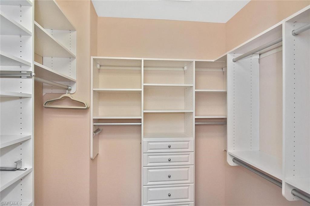 The large walk-in closet is configured with custom shelving and drawers.