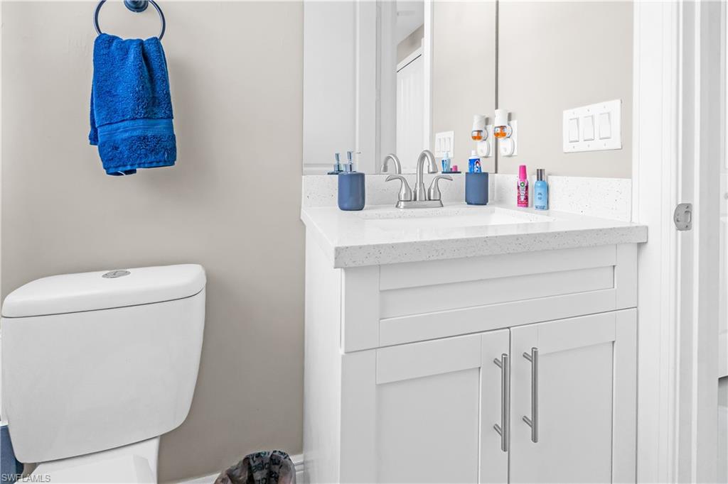 Bathroom featuring a white vanity with slab-style doors, silver-finish hardware, and a light-toned countertop with an integrated sink