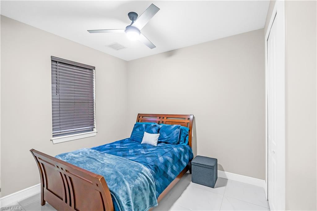 Bedroom #2 featuring light neutral walls, a window with horizontal blinds, a ceiling fan with integrated lighting, and light-toned tile flooring
