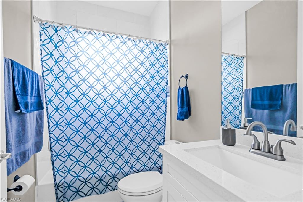 Full bathroom featuring a white vanity with integrated sink, brushed nickel faucet, and a large wall-mounted mirror