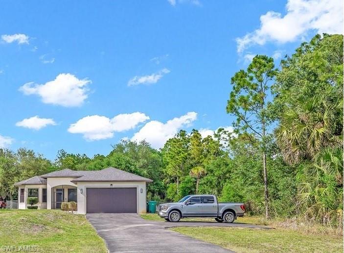 Contemporary single-story residence featuring a two-car garage, paved driveway, stucco exterior, and a screened front entry