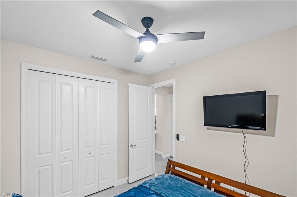 Bedroom #2 featuring a ceiling-mounted fan with integrated lighting, dual bifold closet doors, and light-toned walls