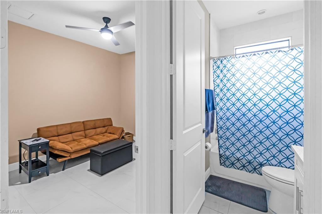 Bedroom #3 and or den with neutral wall tones and a ceiling fan, complemented by a full bathroom featuring a tub/shower combination with white subway tile surround and a transom window