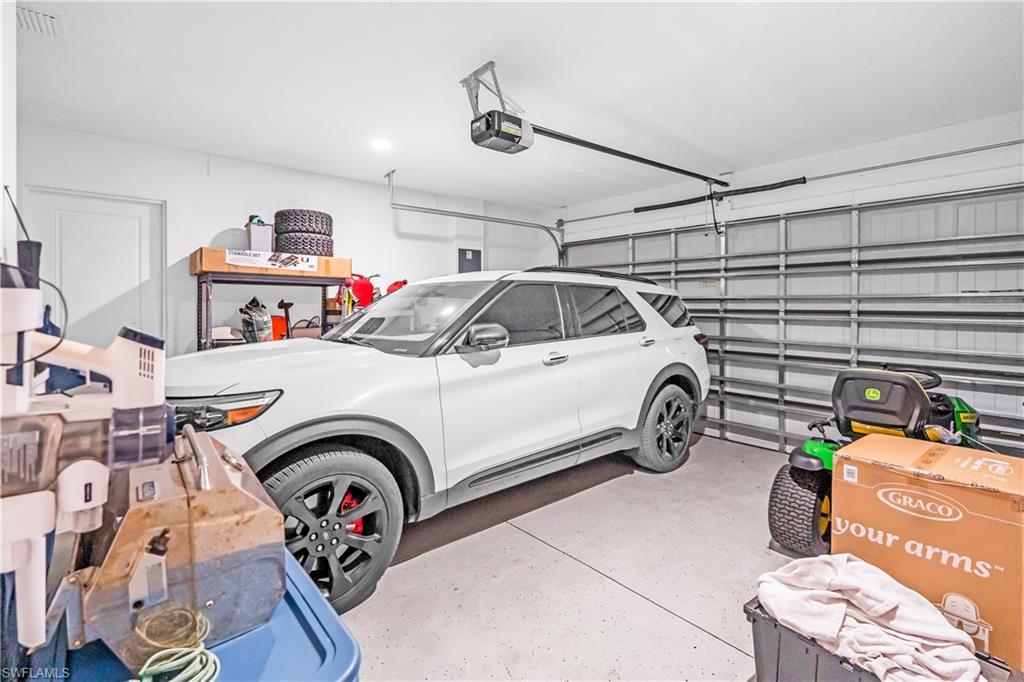 Spacious garage featuring a sectional overhead door, automatic opener, and a side access door