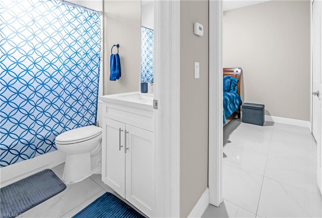 Bathroom featuring a white vanity with an integrated sink, polished chrome hardware, and a toilet