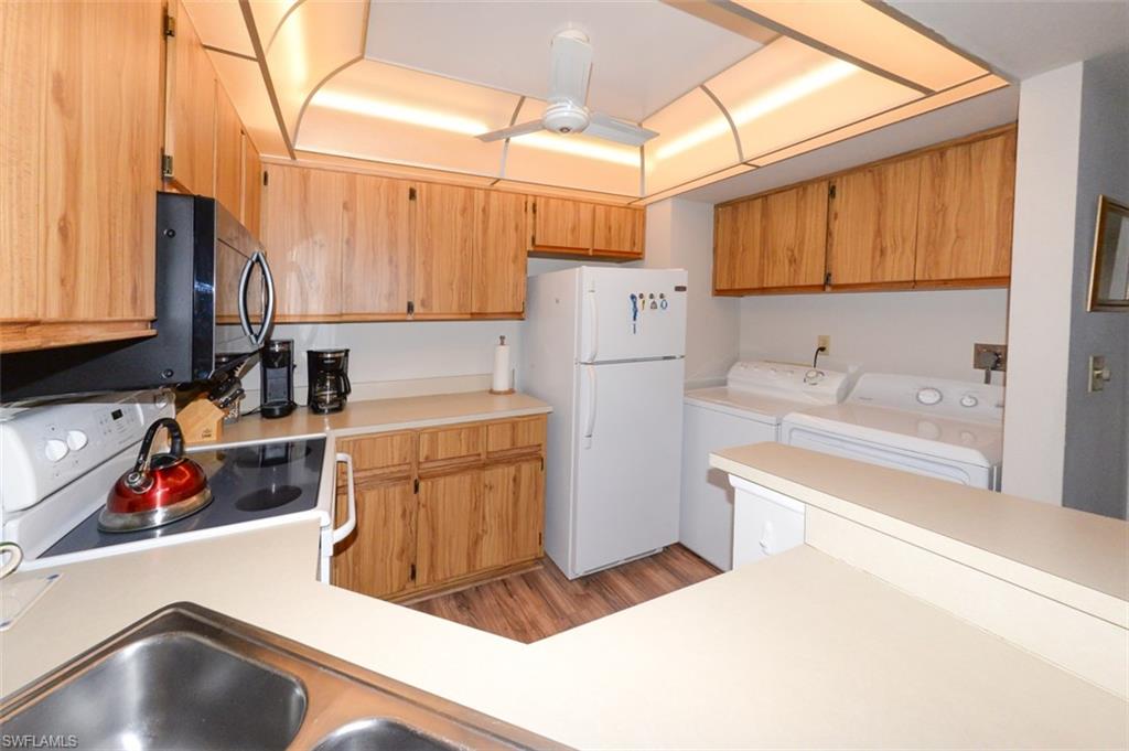Kitchen features ample wood cabinetry and counter space. Shows Laundry closet area to right