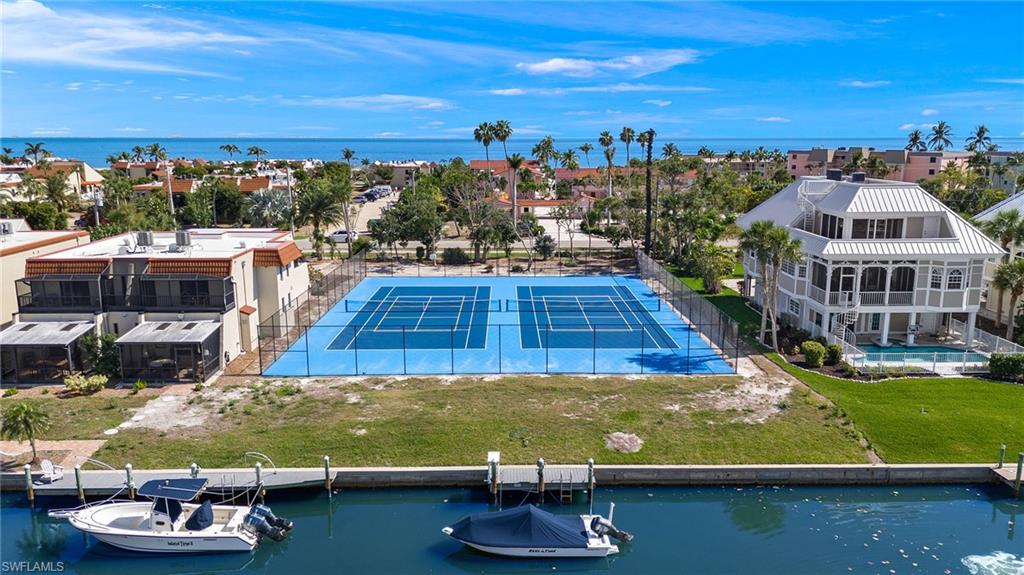 Property featuring a tennis court, private dock access, a spacious two-story residence with multiple balconies, and a private pool area