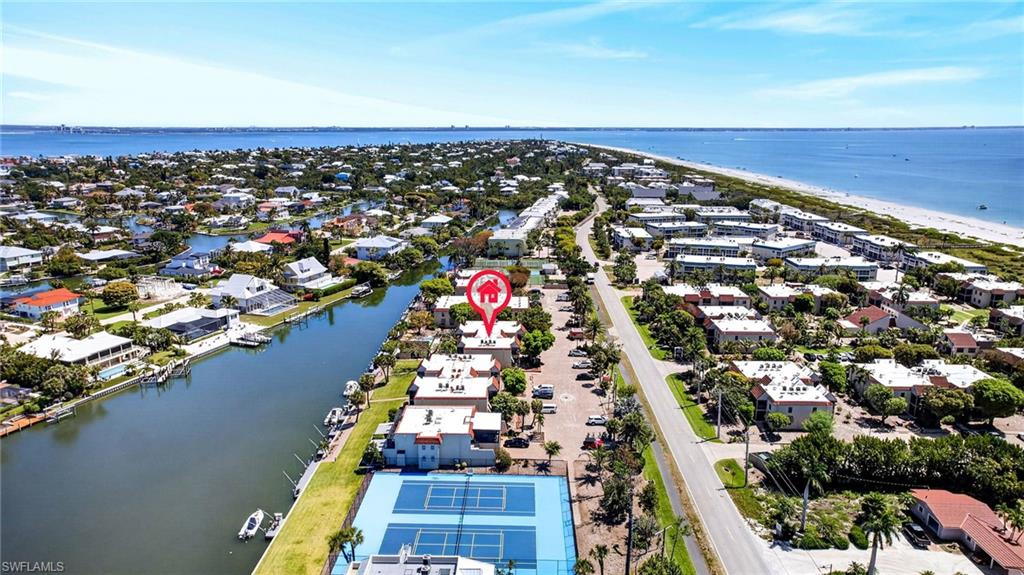 Coastal community featuring waterfront canals, a sandy beach, and a tennis court