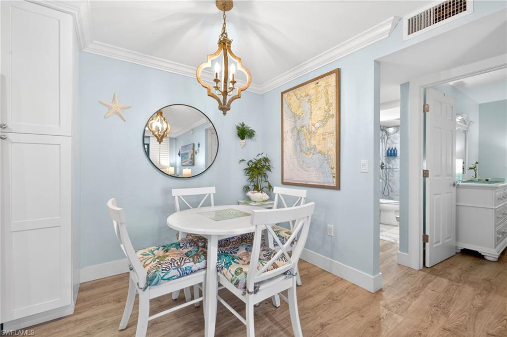 Dining area featuring wood-finish flooring, white cabinetry, and a decorative light fixture