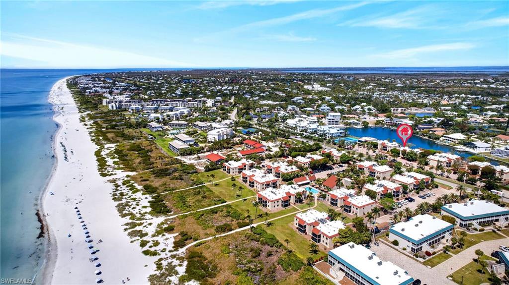 Aerial perspective showcasing a coastal community with extensive white sand beaches and clear blue waters