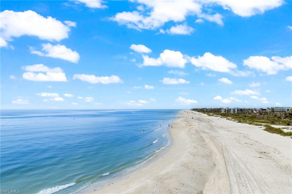 Expansive sandy beach bordering the ocean, featuring a long coastline with visible structures set back from the shore