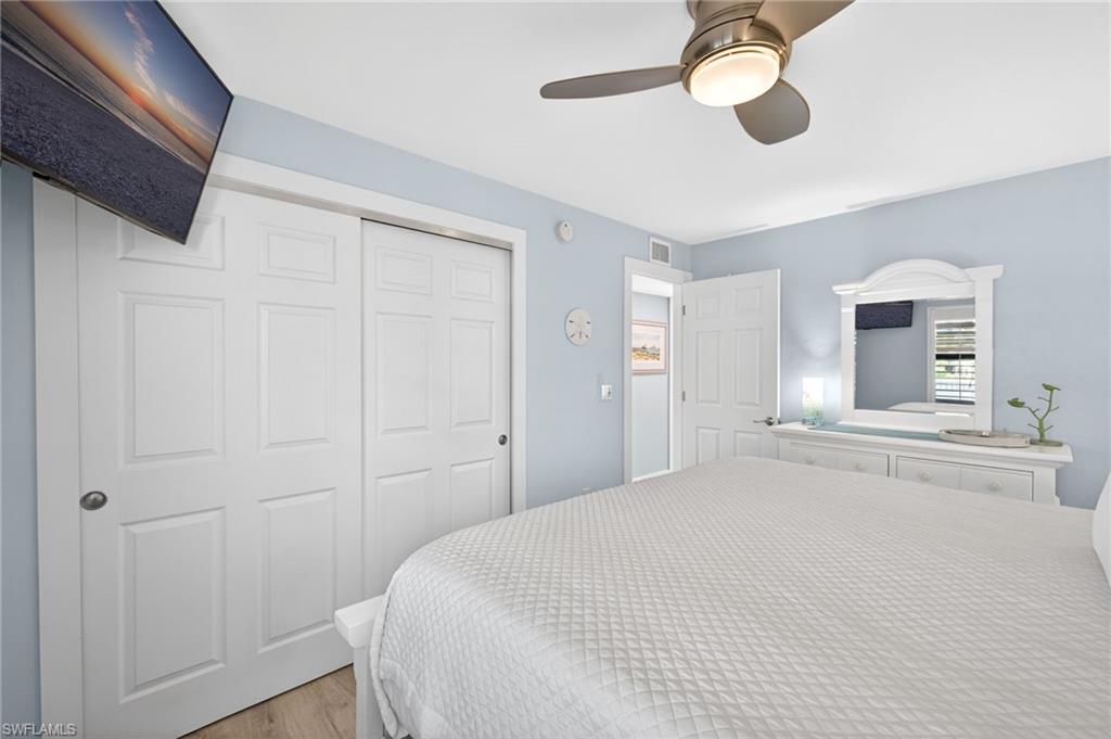 Bedroom featuring light blue walls, wood-finish flooring, and a ceiling fan with integrated lighting
