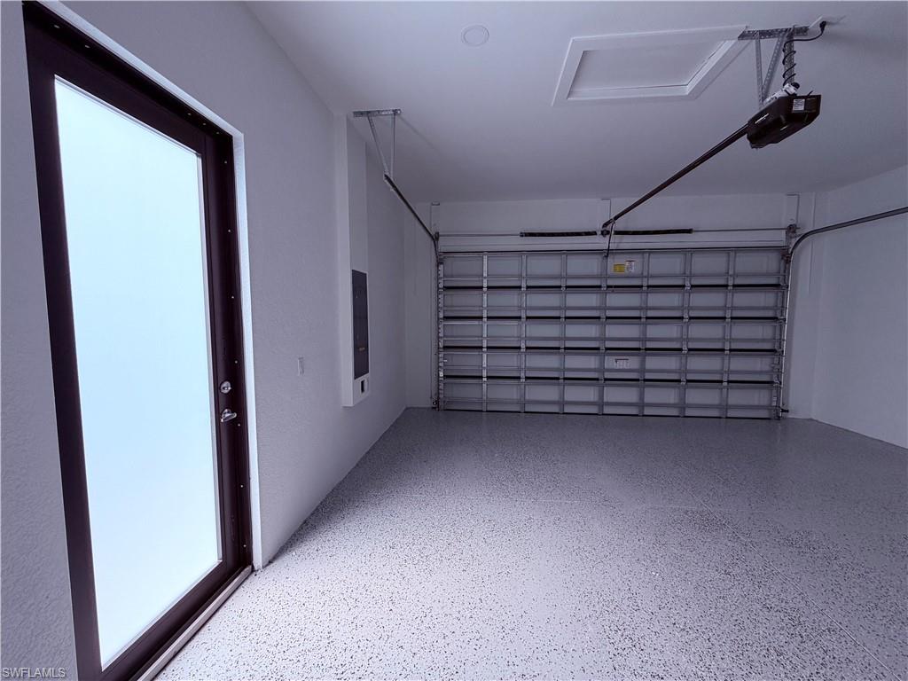 Garage space featuring a frosted glass entry door, an automatic garage door opener, and a speckled epoxy floor finish