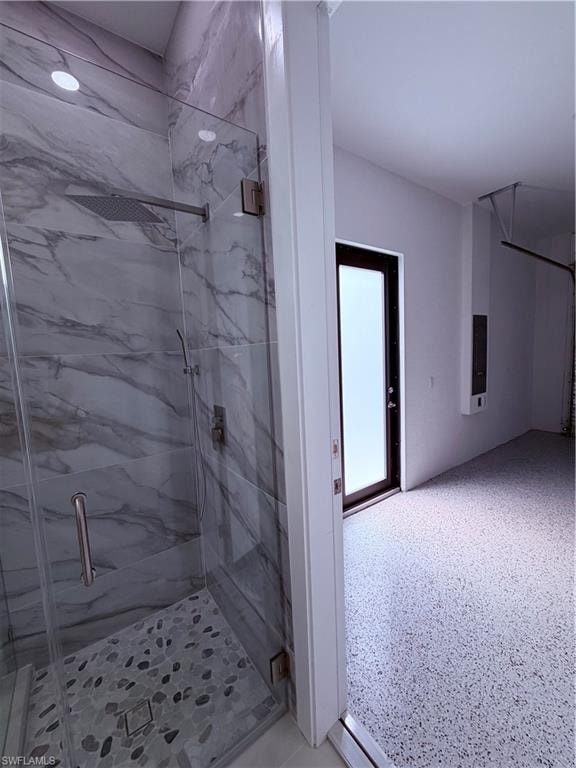 Frameless glass shower with large format marble-effect tile and pebble-style shower pan