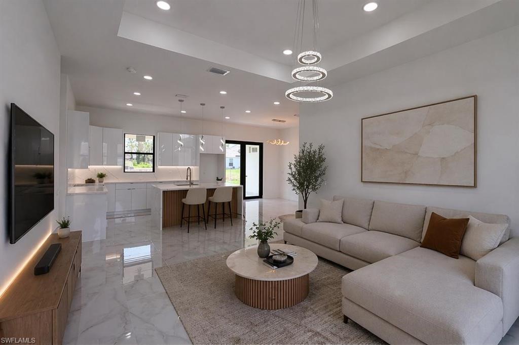 Spacious open-concept interior featuring light-toned flooring, high ceilings with recessed lighting, and a contemporary kitchen with white cabinetry and an island