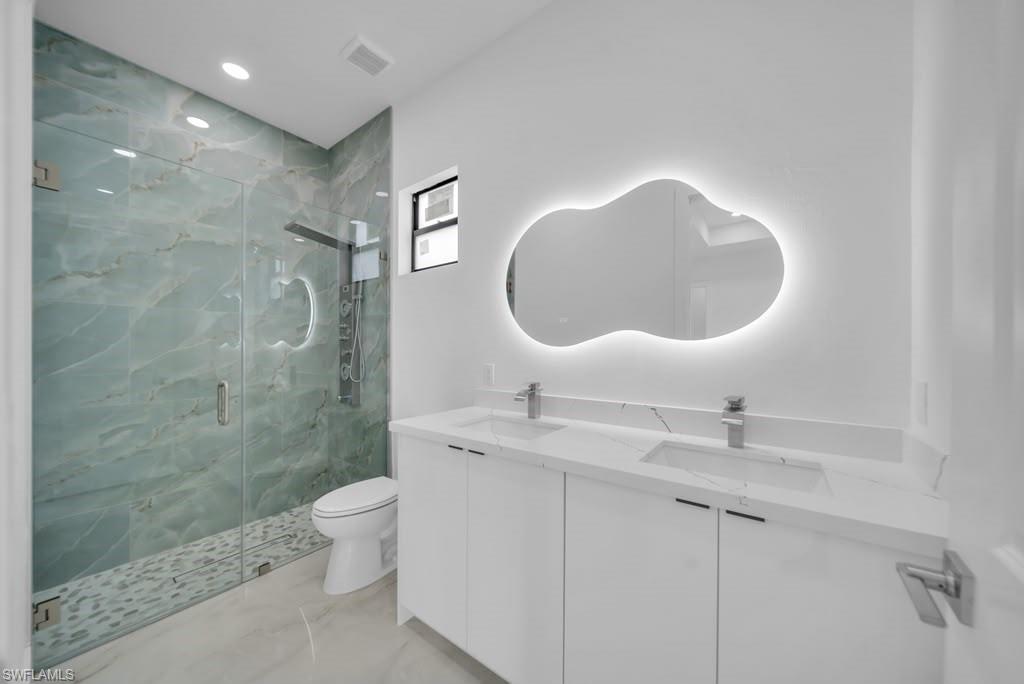 Modern bathroom featuring a dual vanity with white cabinetry, integrated sinks, and polished chrome faucets