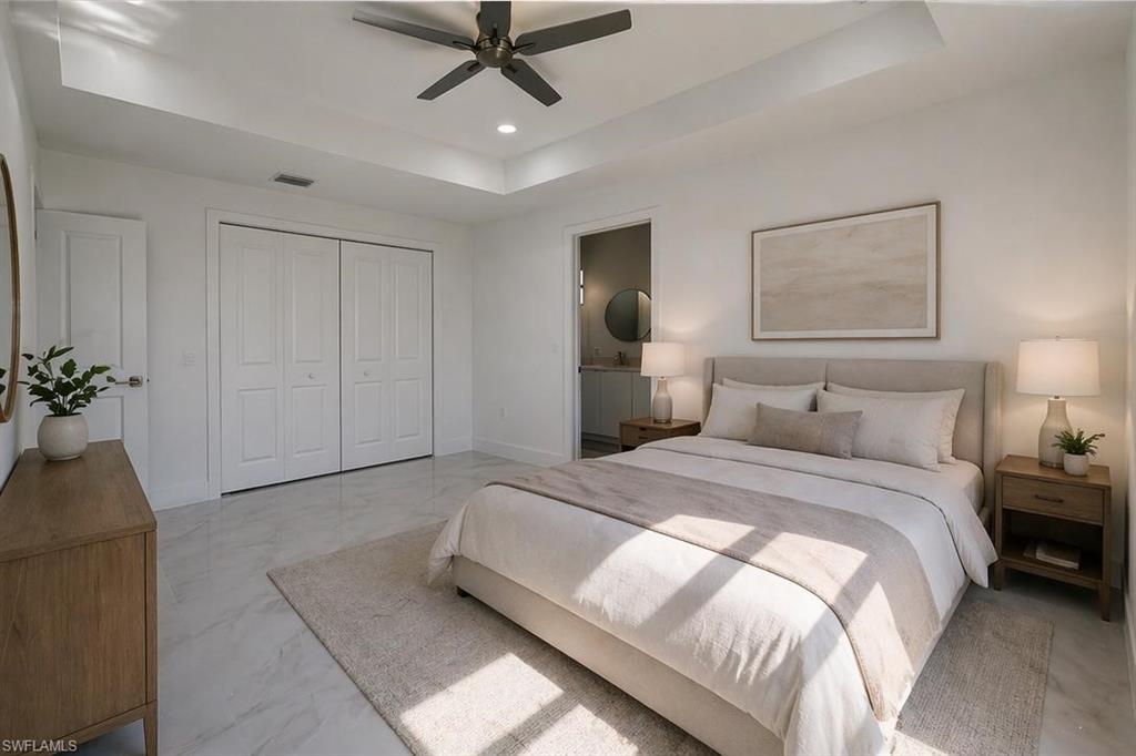 Bedroom featuring high ceilings with a tray detail, a ceiling fan, and light-toned tile flooring