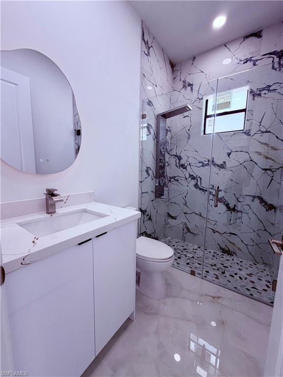 Modern bathroom featuring a custom-shaped backlit mirror, white vanity with integrated sink, and a shower enclosure with floor-to-ceiling marble-look tile