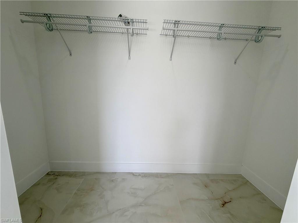 Walk-in closet featuring light-toned flooring, white walls, and two wire shelving units