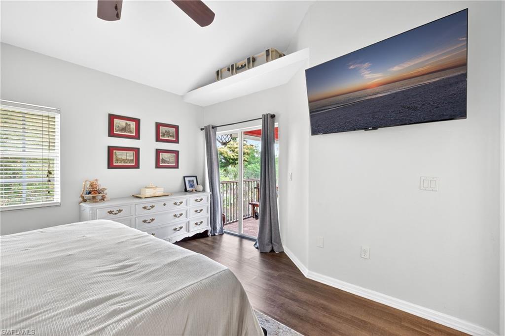 Primary Bedroom w/ vaulted ceilings, a ceiling fan, wood-finish flooring, and a sliding glass door leading to an outdoor deck