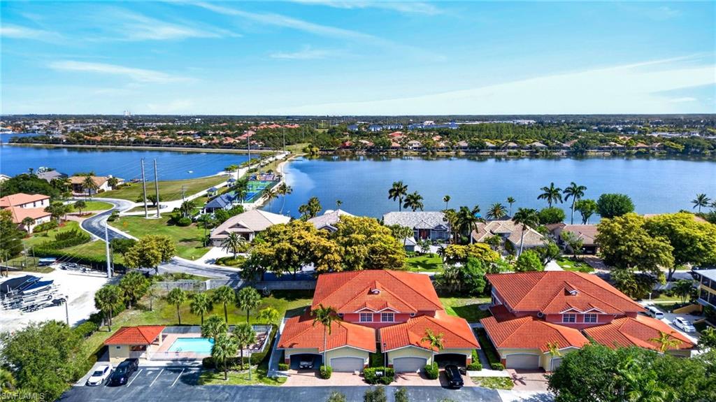 Waterfront community featuring multiple residences with terracotta tile roofs, an outdoor swimming pool, and dedicated parking
