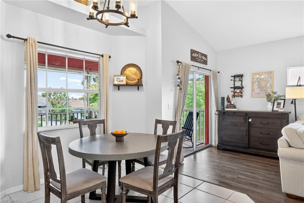 Dining area with vaulted ceilings, featuring a circular table, two window openings, and a sliding glass door to a balcony