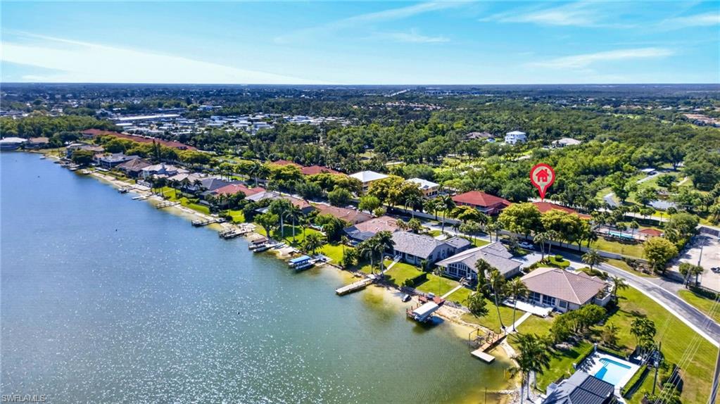 Waterfront property featuring individual docks for watercraft, mature landscaping, and a clear blue sky