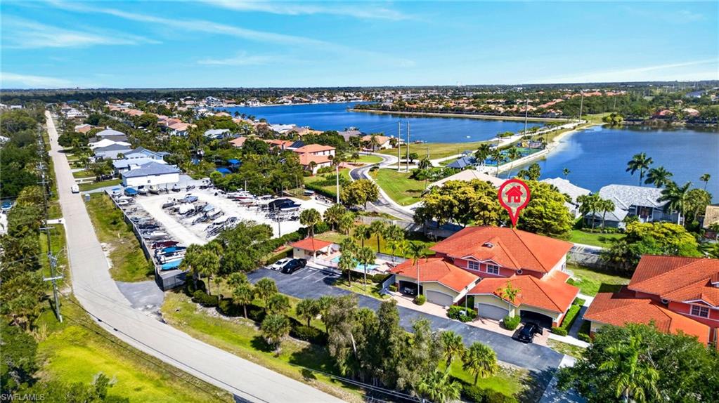 Waterfront property featuring a red tile roof, multiple garages, and a paved driveway