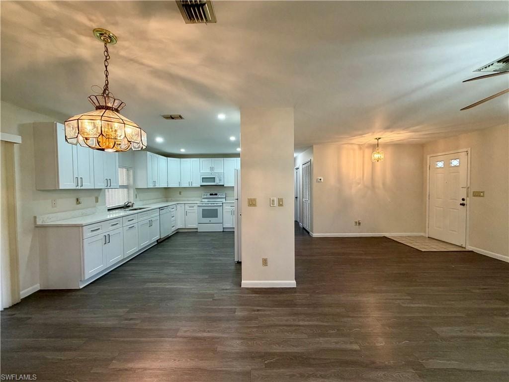 Kitchen and living area featuring wood-finish flooring, white cabinetry, integrated appliances, recessed lighting, and a decorative ceiling fixture